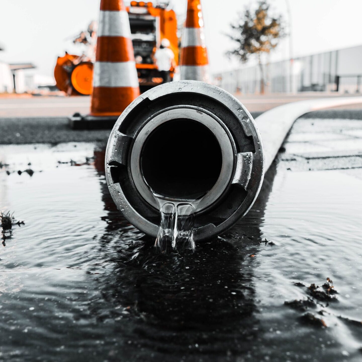A selective closeup shot of a gray pipe with water coming out its hole